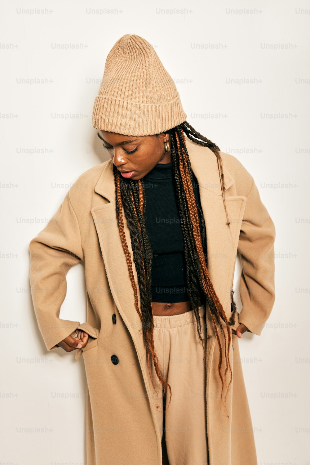 a woman with dreadlocks standing in front of a white wall