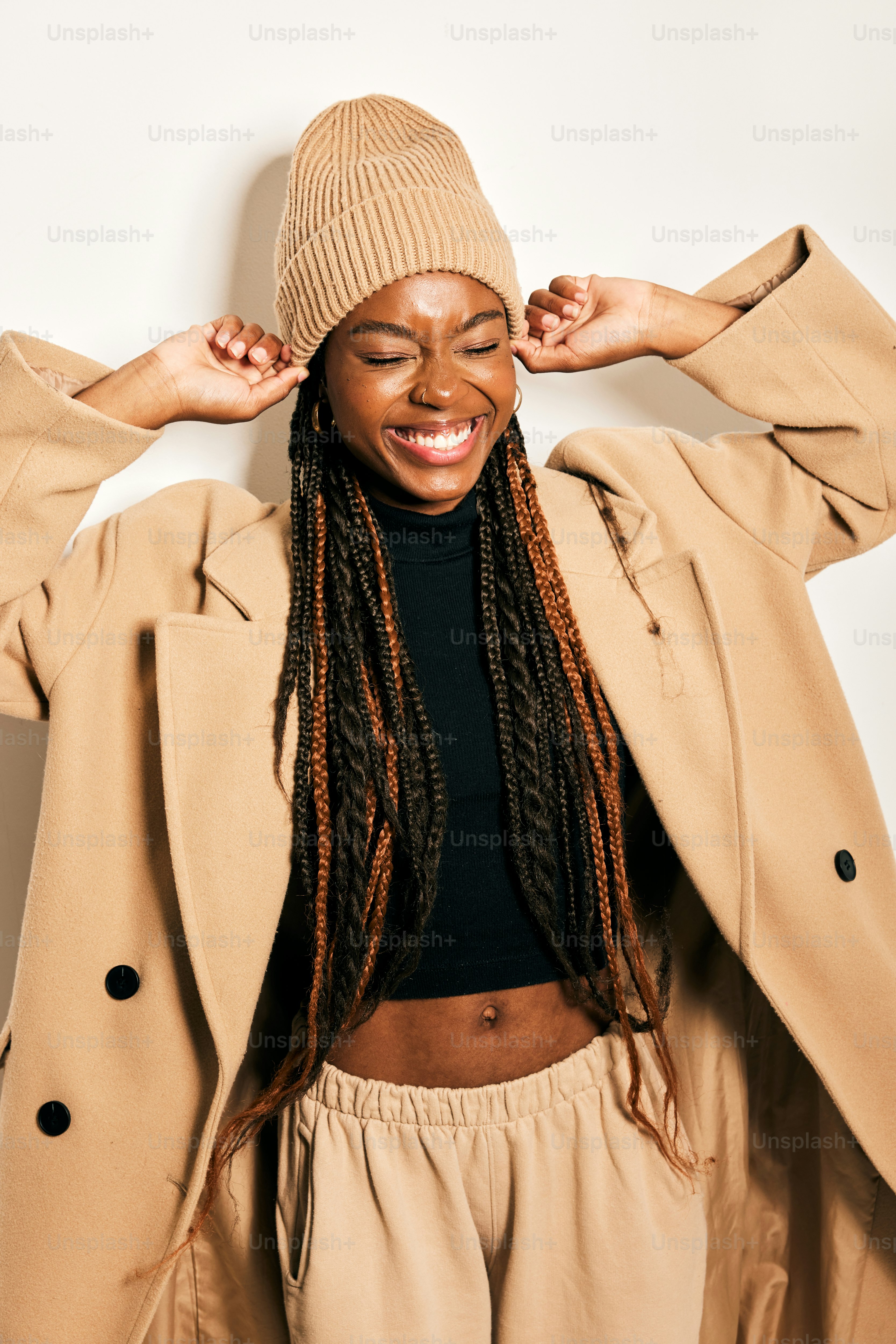 a woman with dreadlocks wearing a tan coat