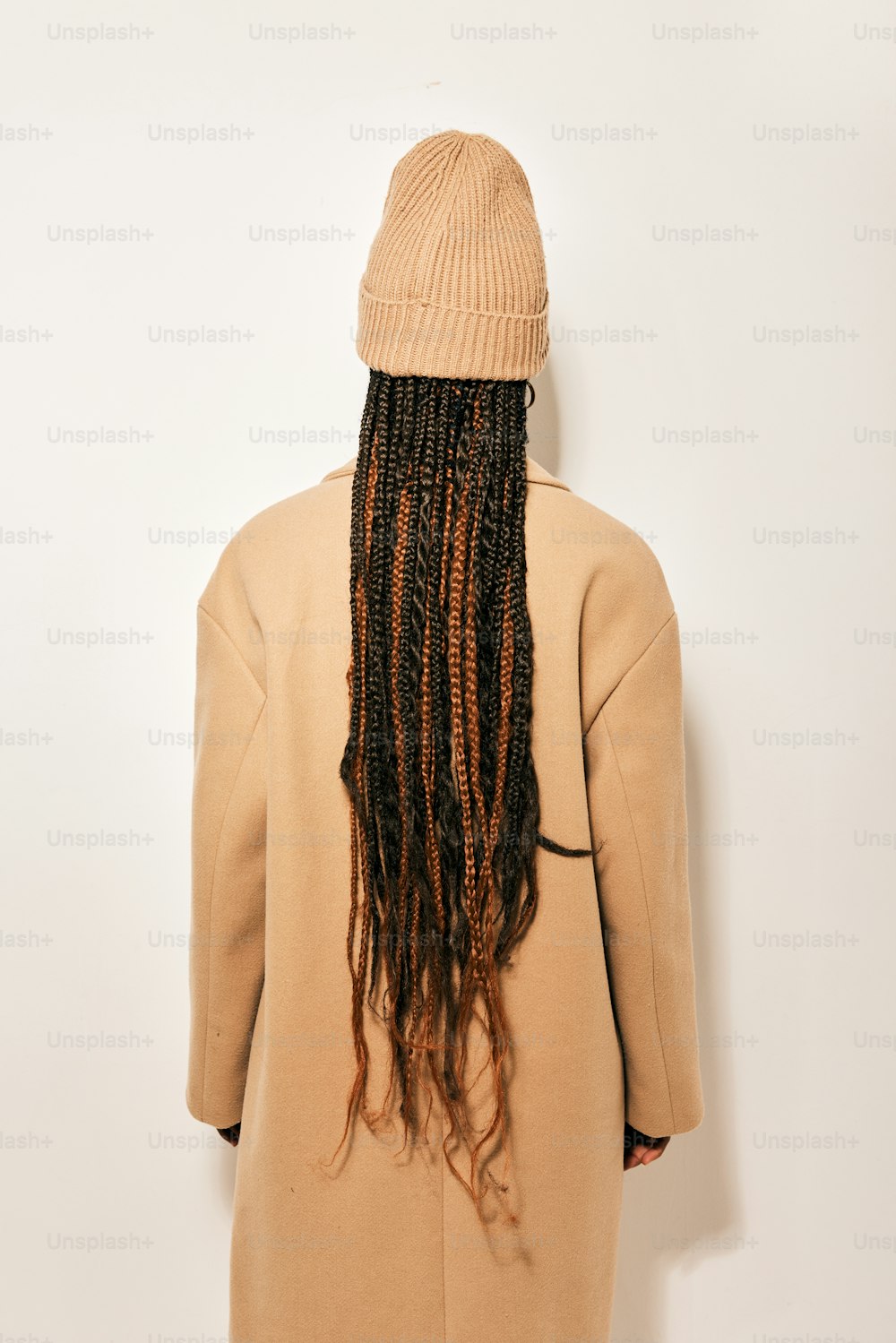a woman with long dreadlocks standing in front of a white wall