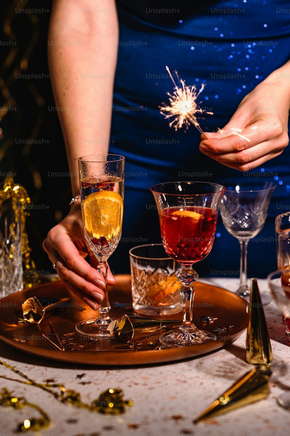 a person holding a sparkler over a tray of glasses
