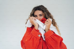 Una donna con una giacca arancione si copre la bocca con un asciugamano bianco