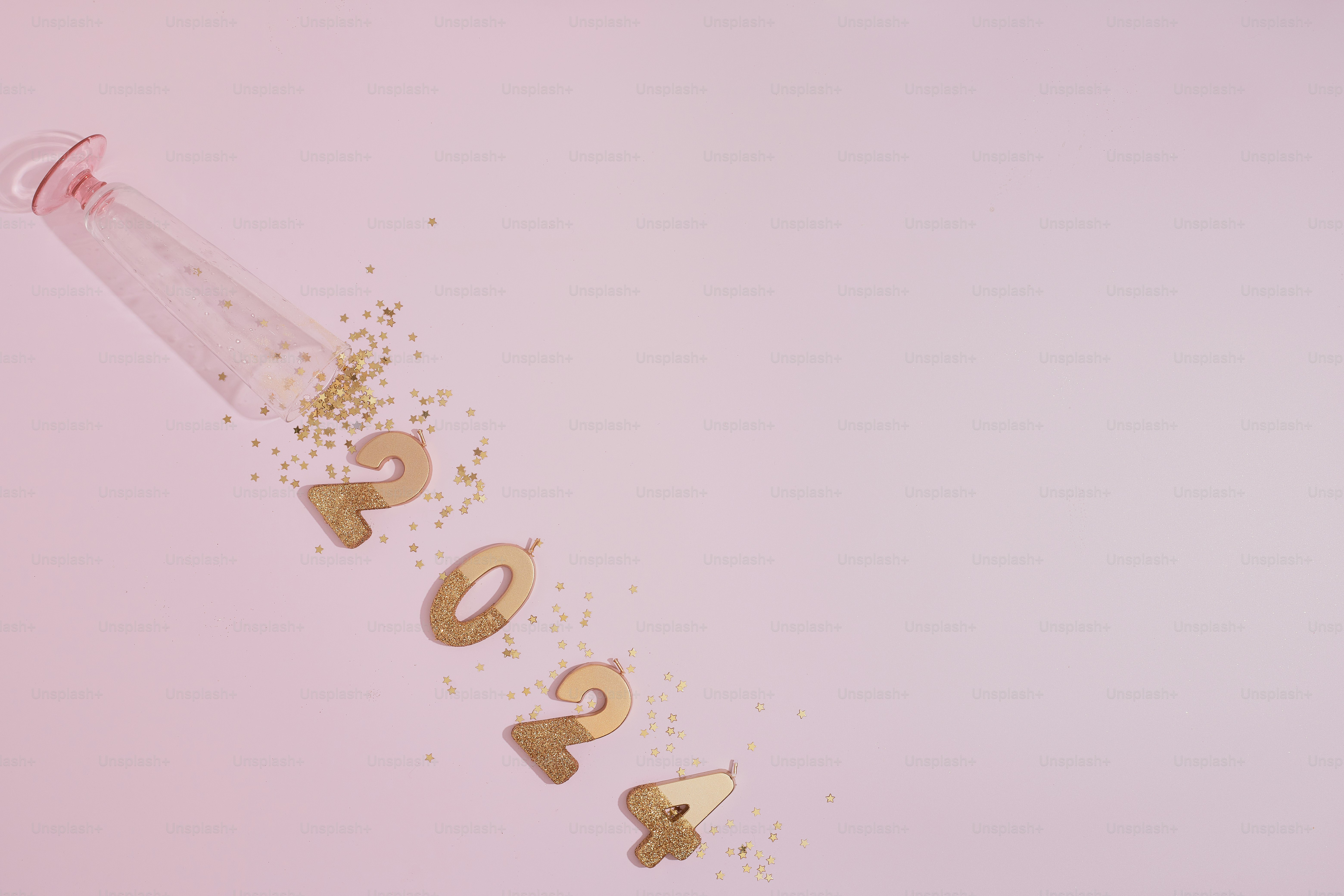 eine mit goldenem Konfetti gefüllte Flasche neben rosa Hintergrund