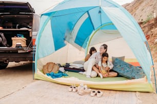 a woman and two children sitting in a tent