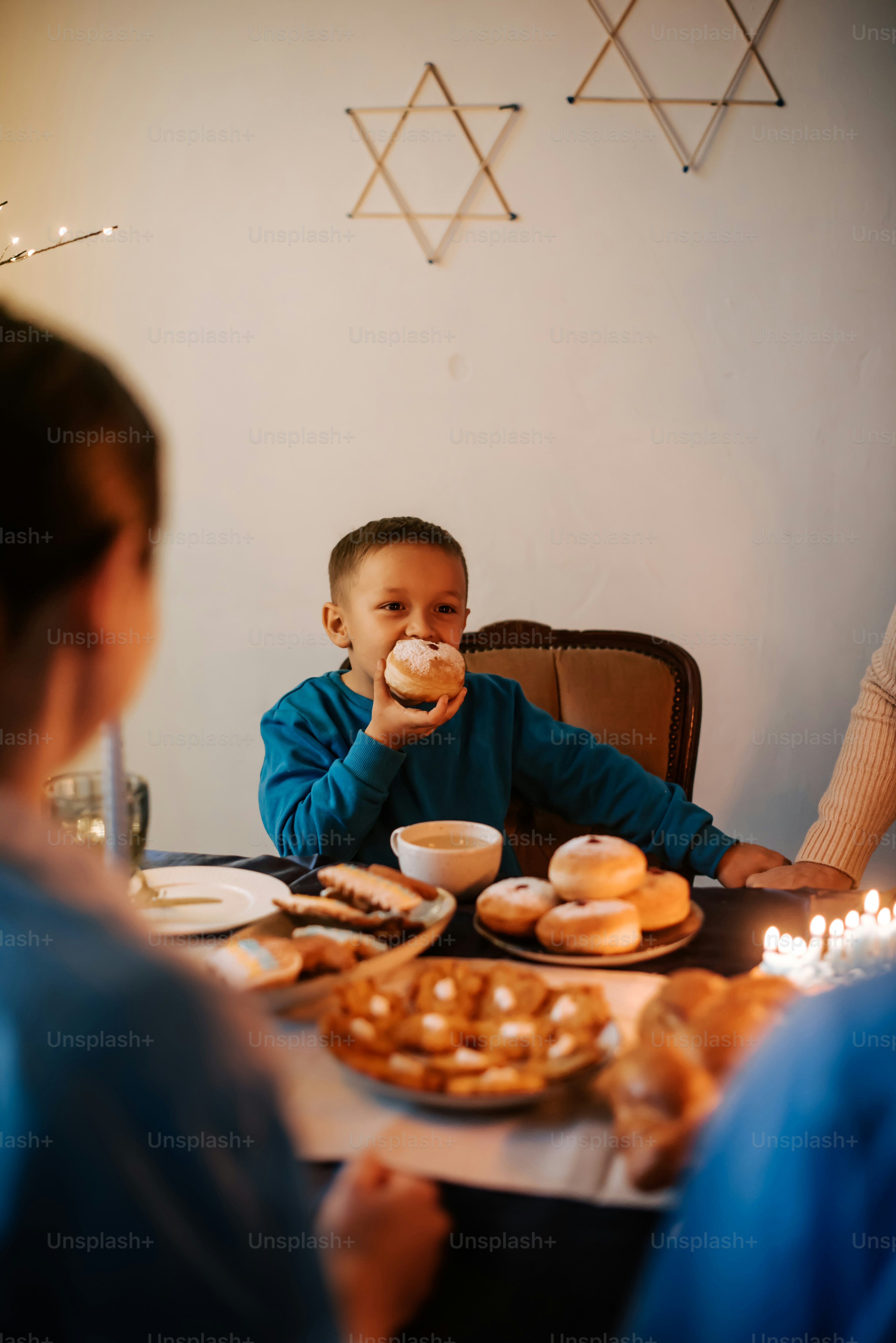 a little boy sitting at a table with a plate of doughnuts