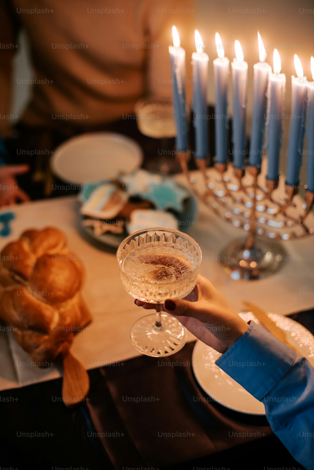 a person holding a wine glass in front of a table with candles