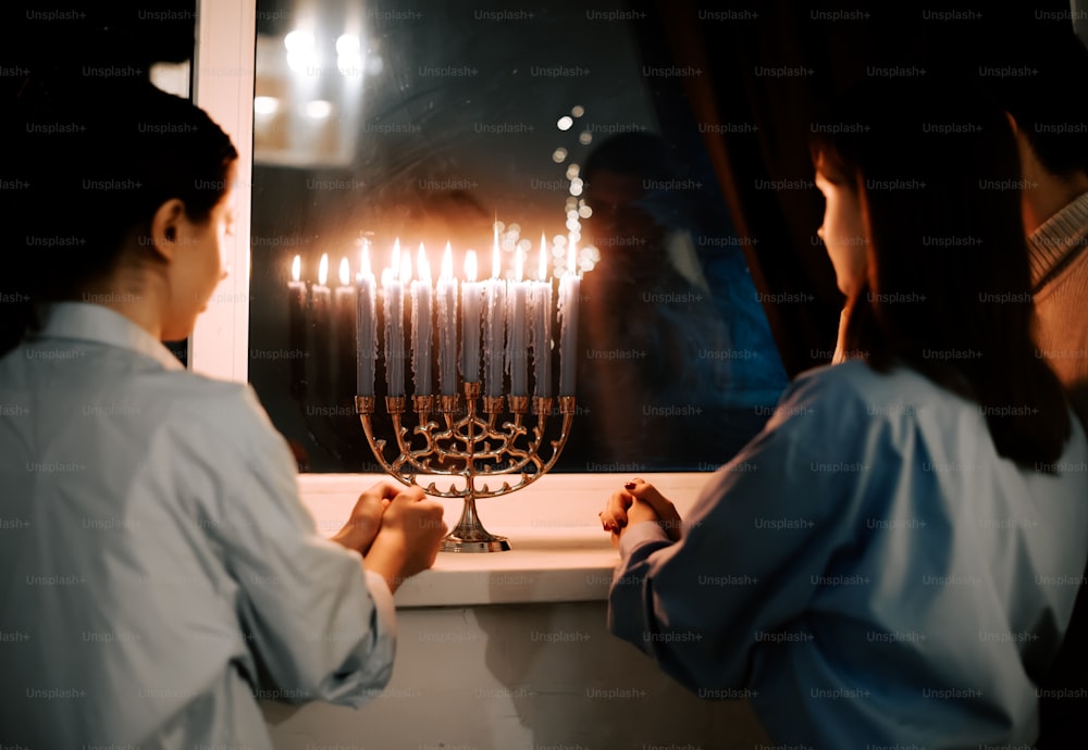 two women looking at a menorah with lit candles