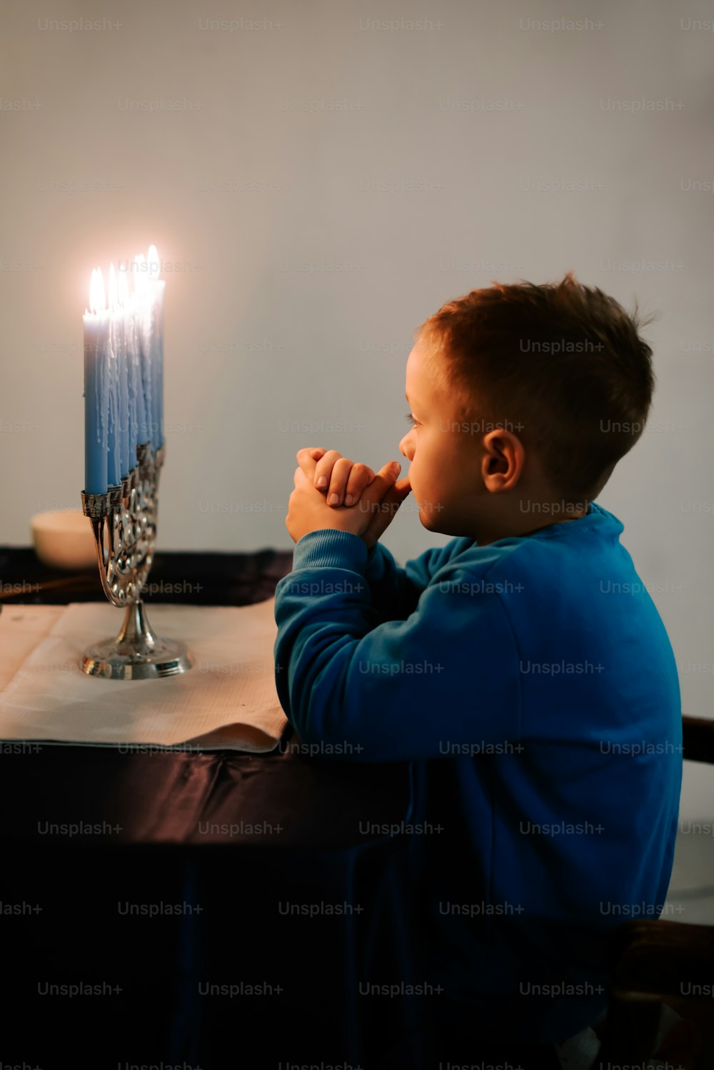 촛불이 켜진 테이블에 앉아 있는 어린 소년