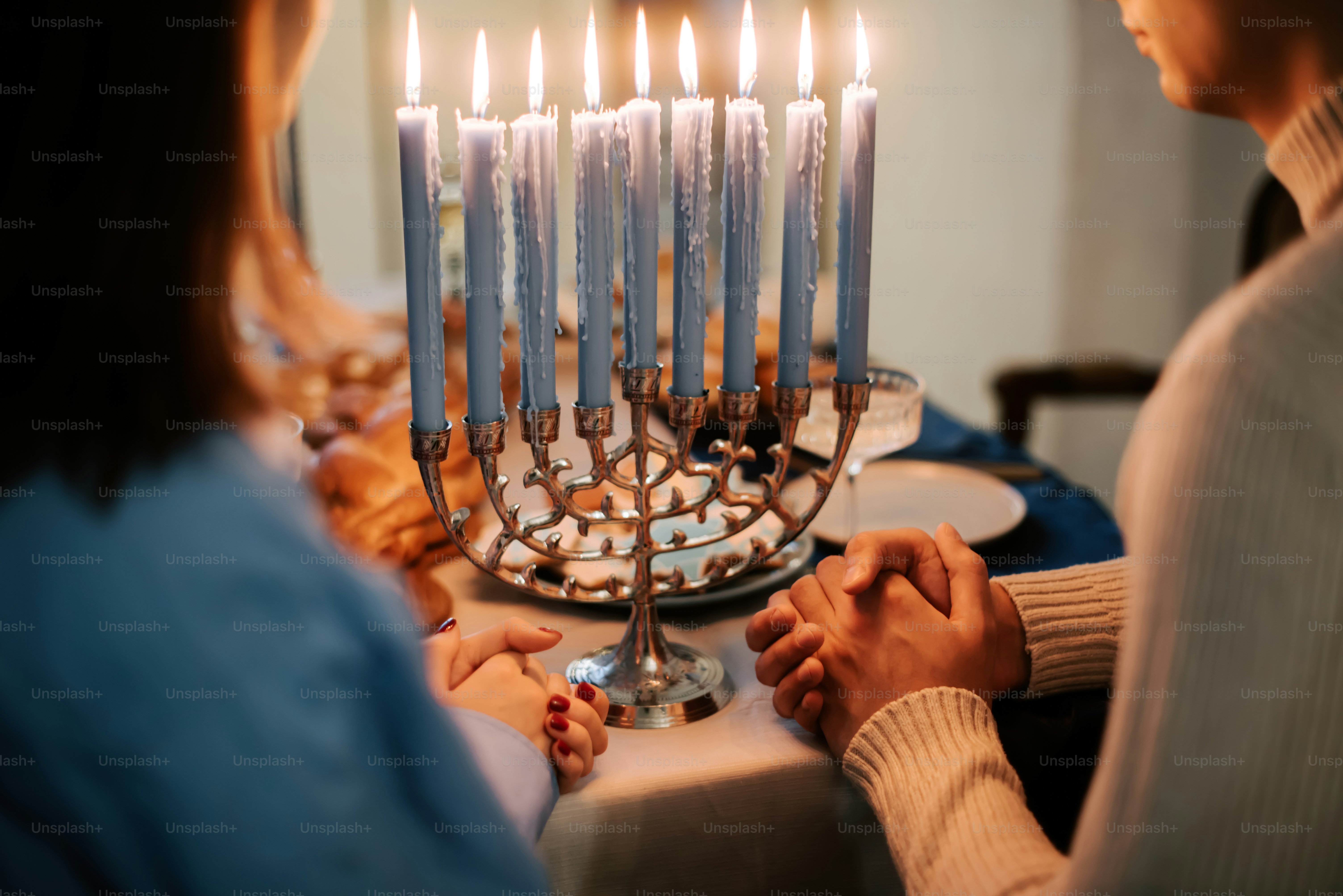 a man and a woman holding hands in front of a menorah