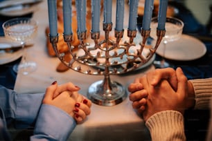 two people holding hands in front of a menorah