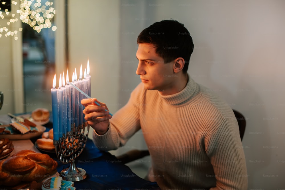 a man holding a lit candle in front of a table