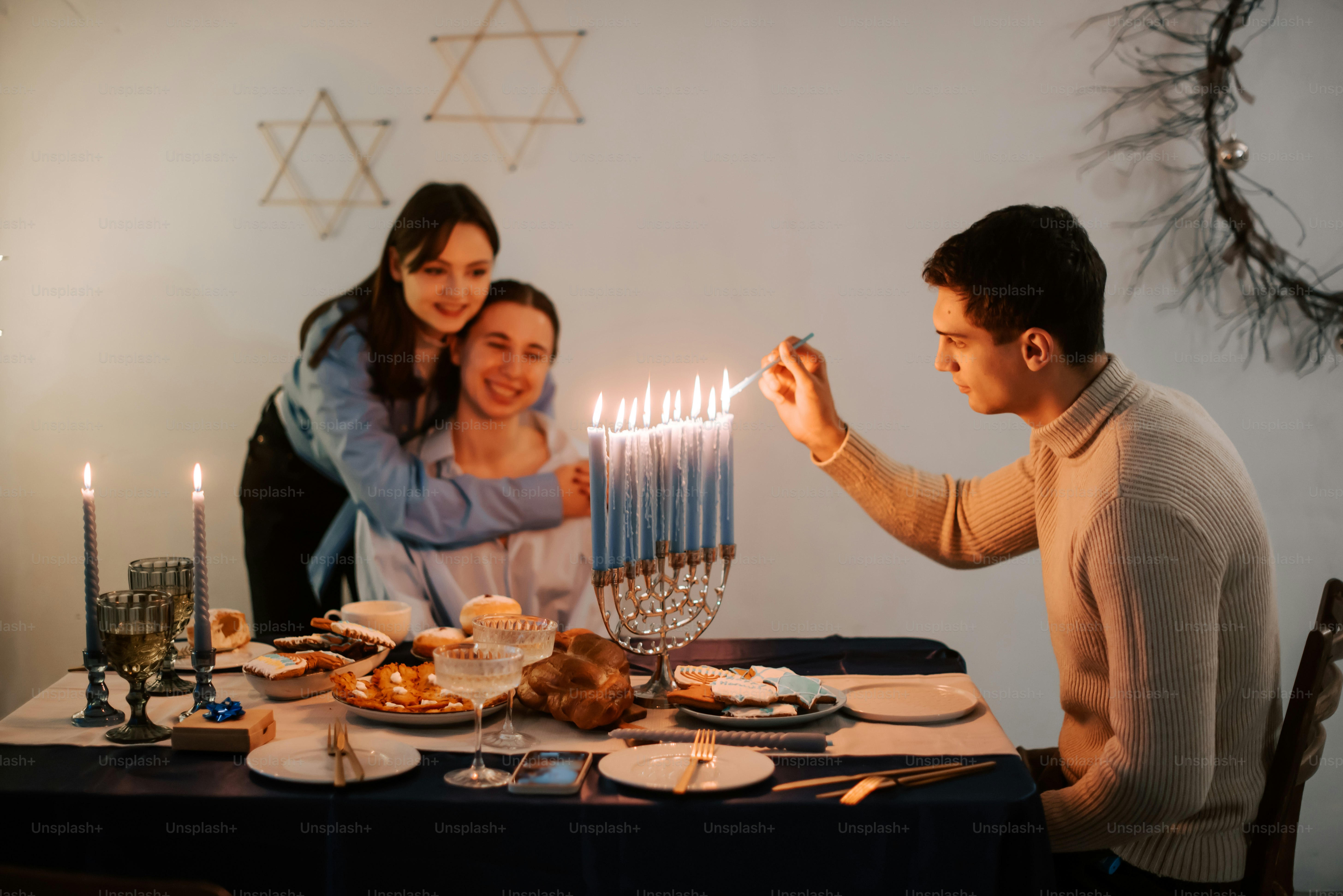 a man lighting a menorah on a table with two women