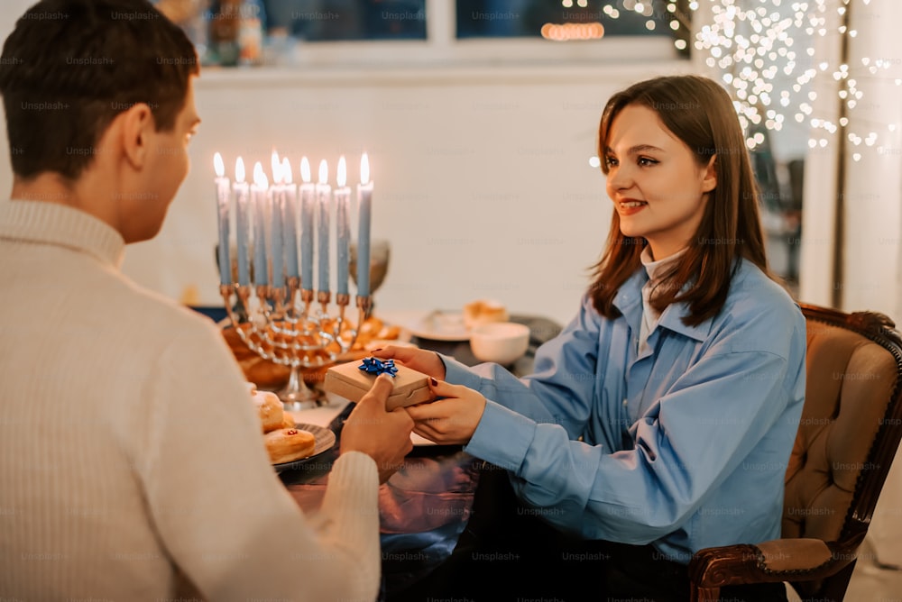 a man and woman sitting at a table with a lit menorah