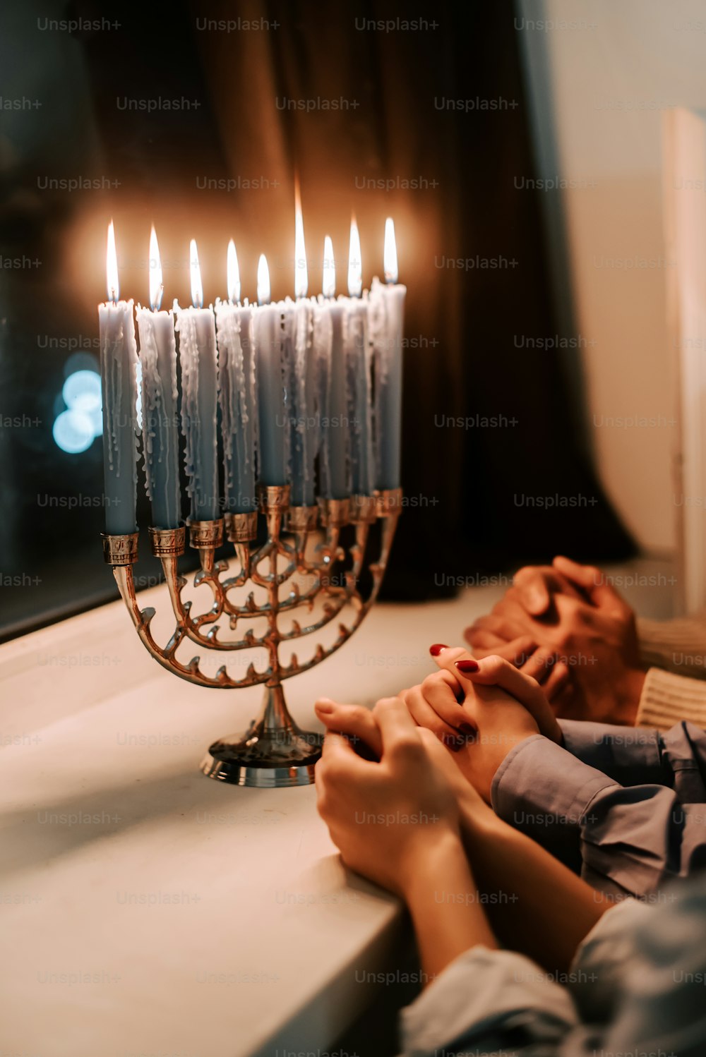 a person sitting in front of a lit menorah