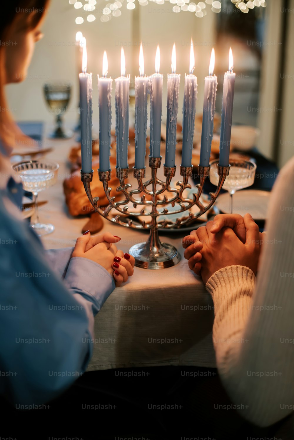 a person sitting at a table with a lit menorah