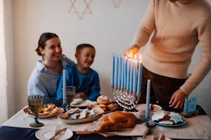 a man and a woman sitting at a table with a lit menorah