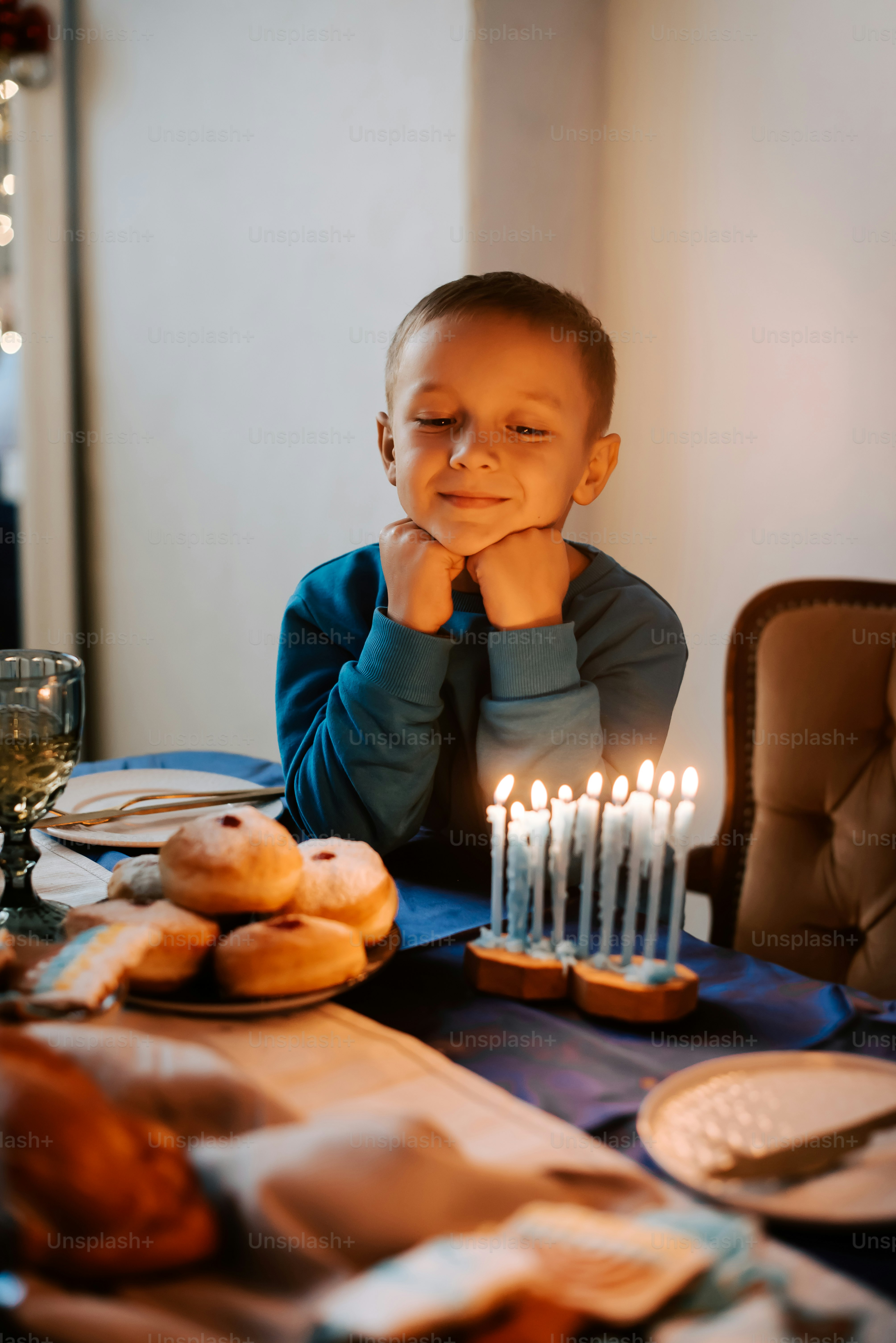 a little boy sitting at a table with a bunch of donuts