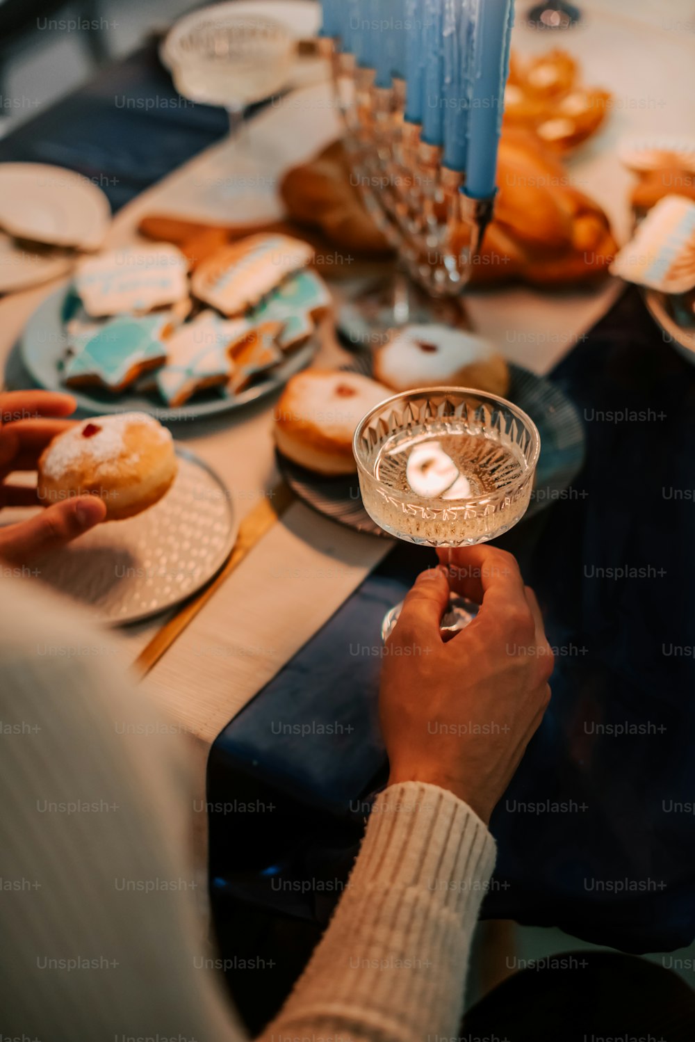 a person holding a lit candle in front of a table full of pastries