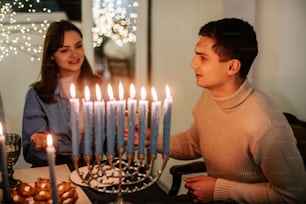 a man and a woman sitting in front of a menorah with lit candles