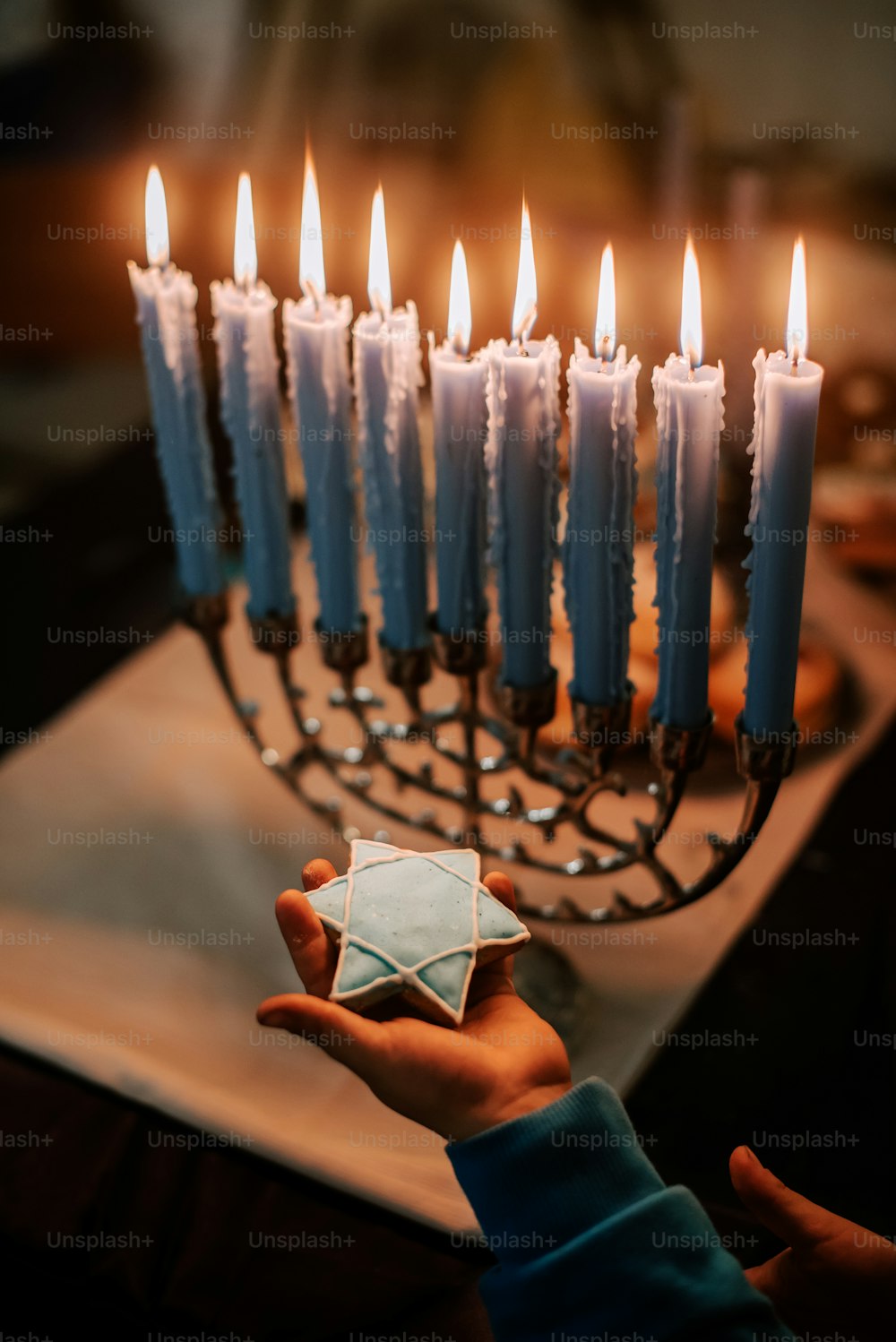 a person holding a paper origami in front of a menorah
