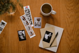 uma mesa de madeira coberta com fotos e uma xícara de café
