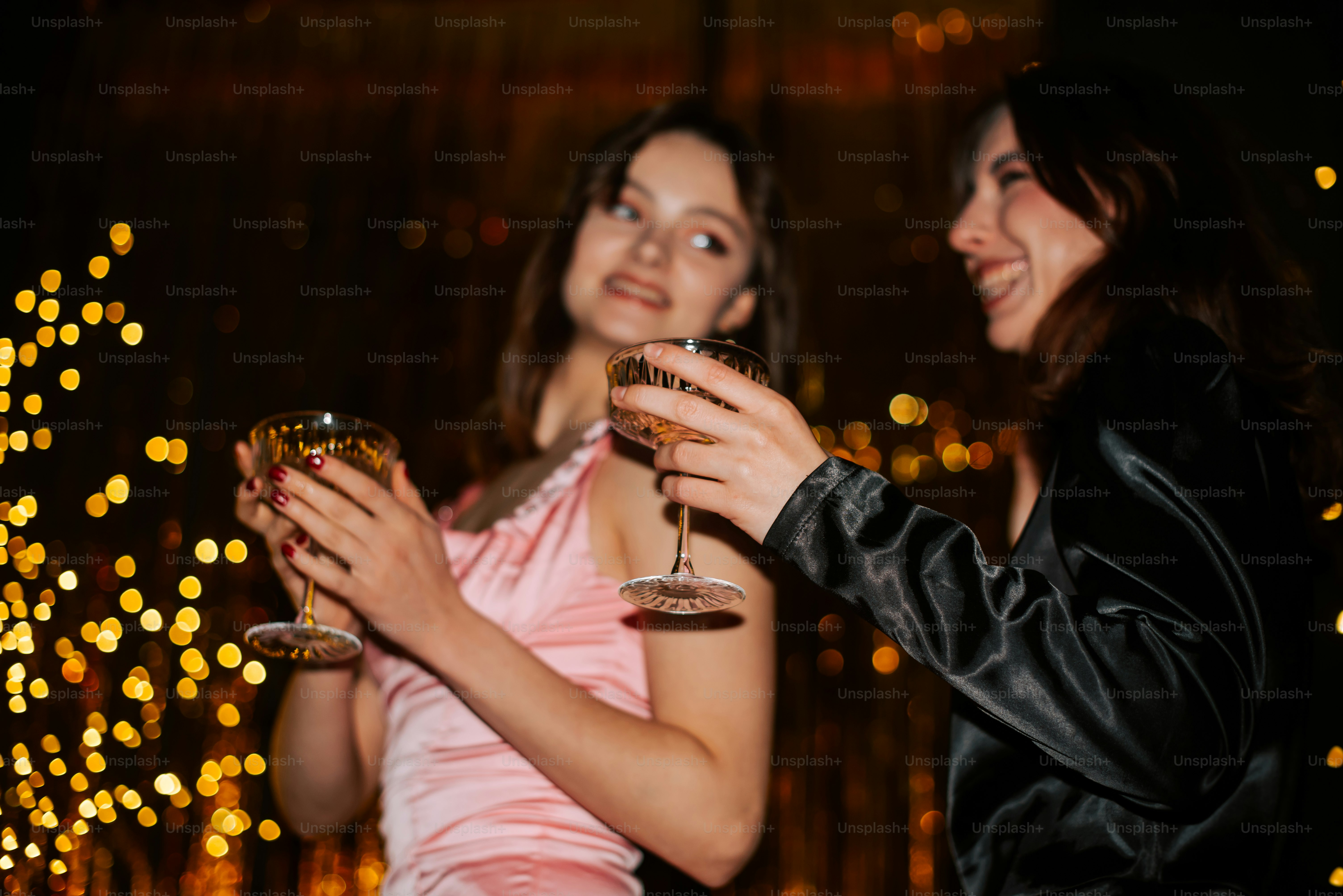 a couple of women standing next to each other holding wine glasses