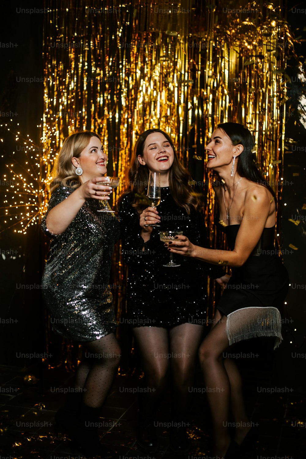 three beautiful women standing next to each other holding wine glasses