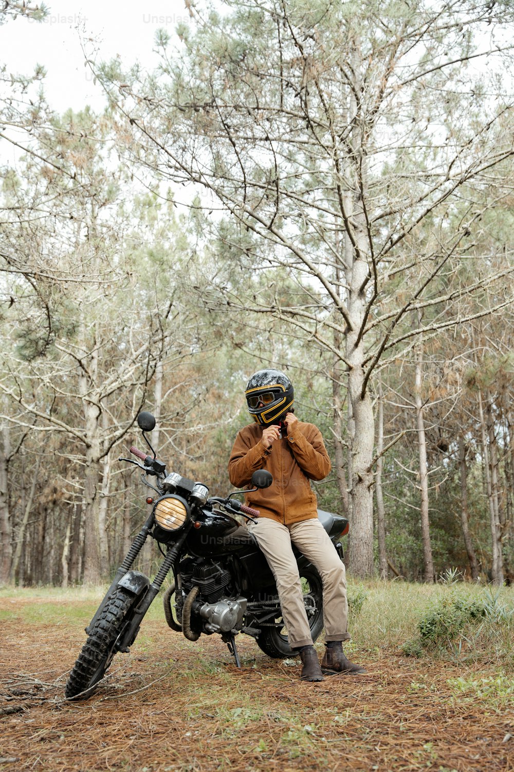 un homme assis sur une moto dans les bois