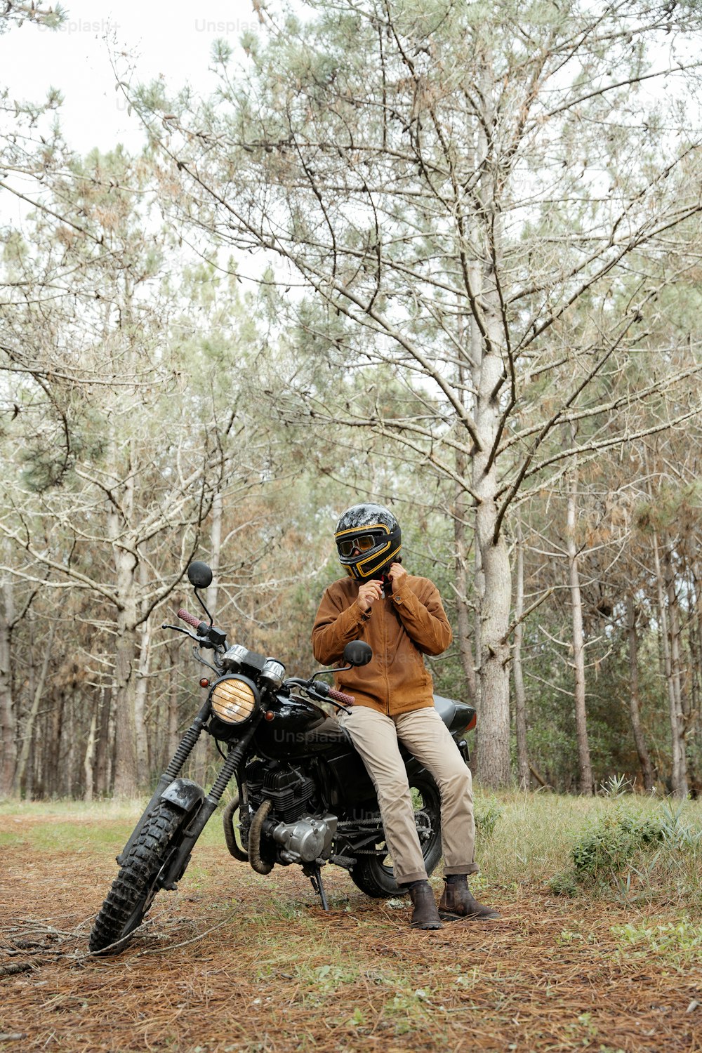 a man sitting on a motorcycle in the woods