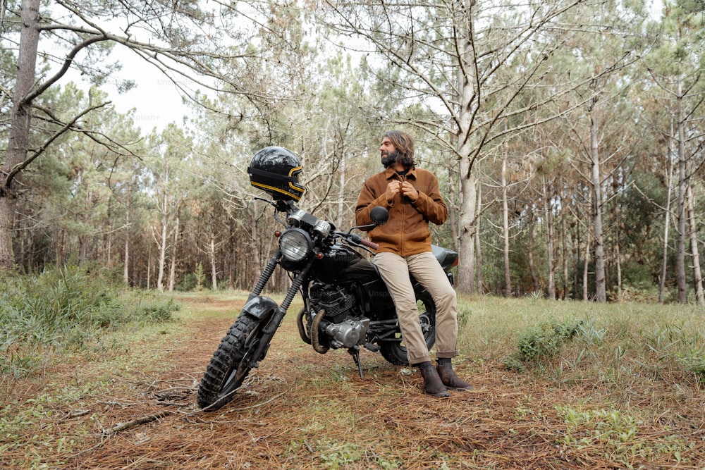a man sitting on a motorcycle in the woods