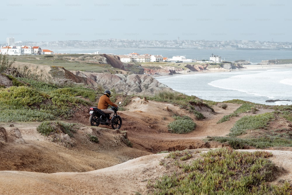 Ein Mann fährt mit einem Motorrad eine unbefestigte Straße neben dem Meer hinunter