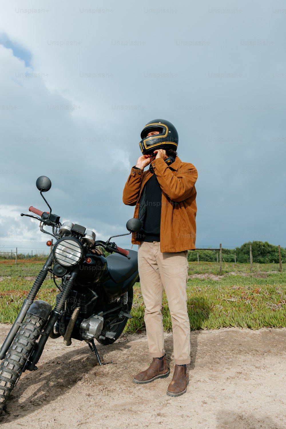 a man standing next to a motorcycle on a dirt road