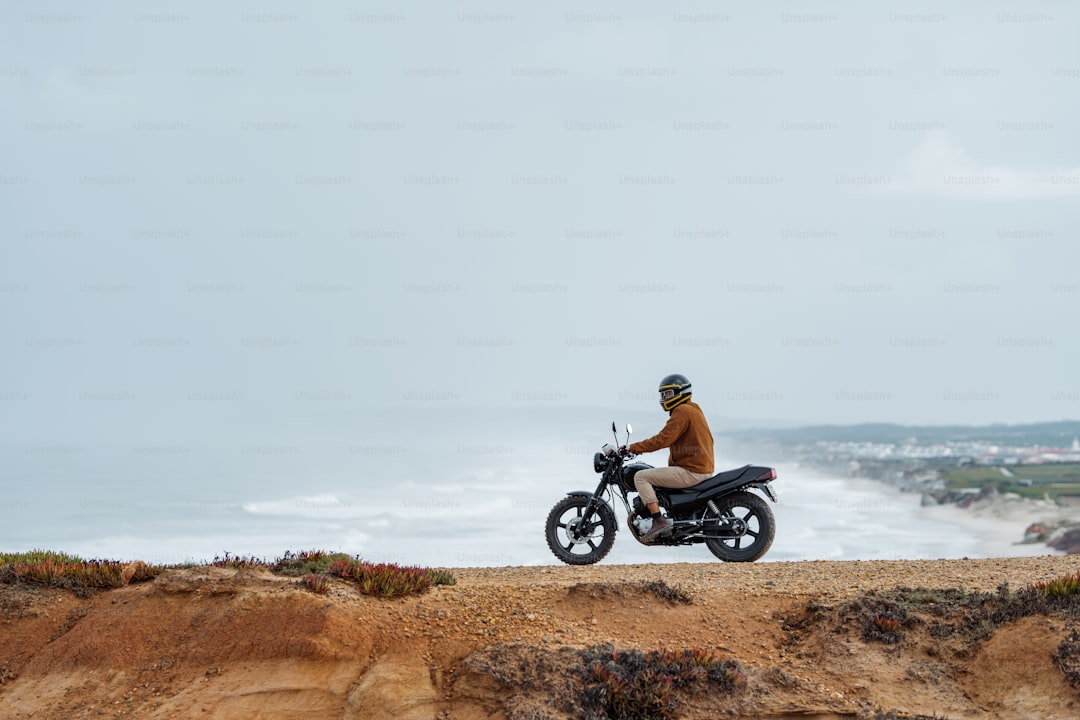 a man riding a motorcycle on top of a sandy beach