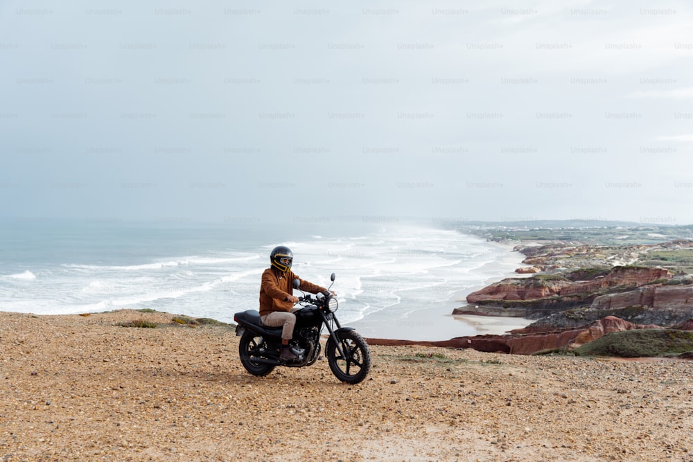 a man riding a motorcycle on top of a sandy beach