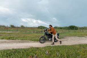 a man walking next to a motorcycle on a dirt road