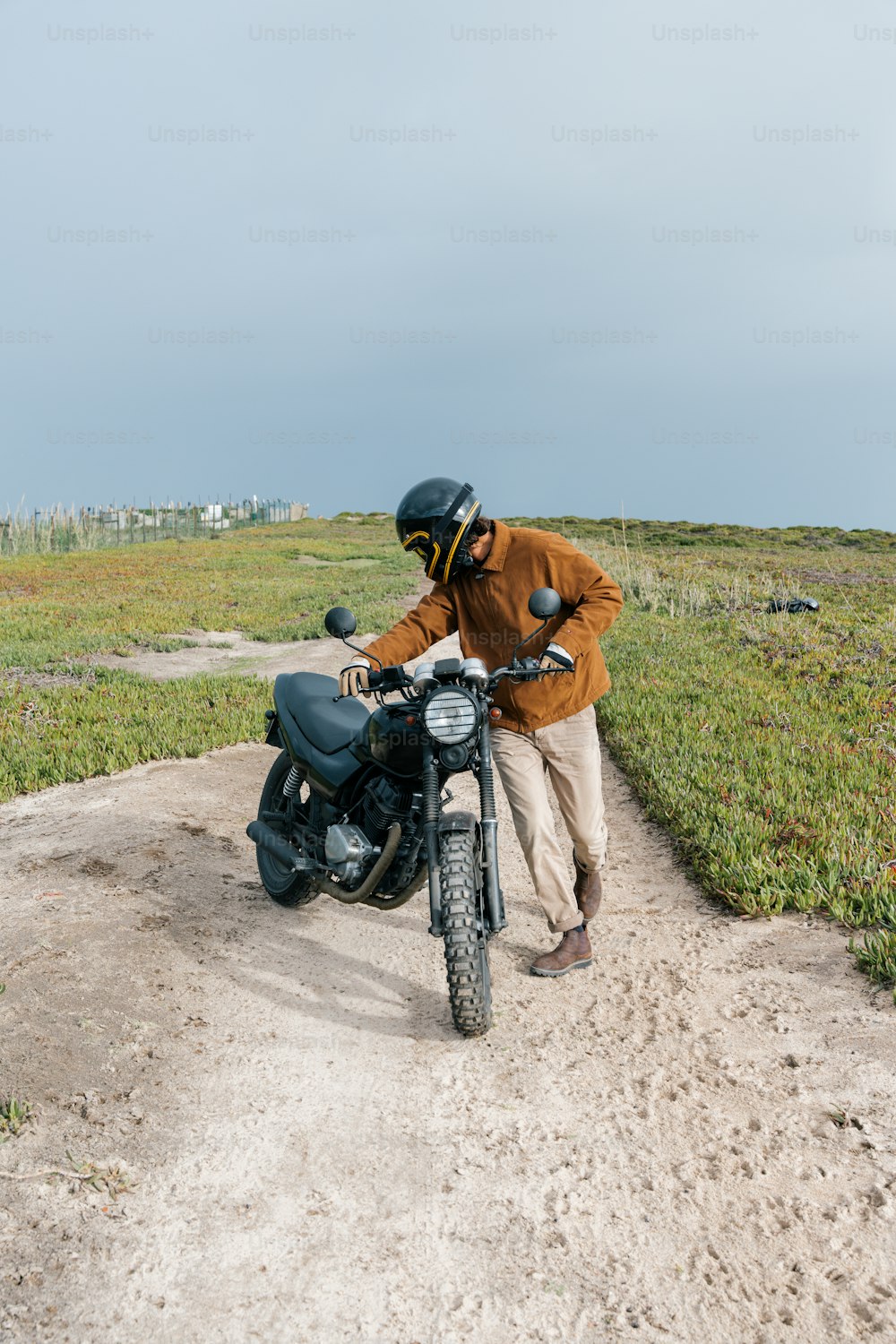 a man standing next to a motorcycle on a dirt road