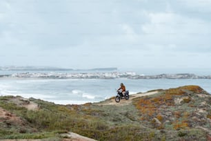 a man riding a motorcycle down a hill next to the ocean