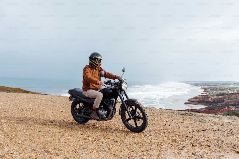 Un hombre montando una motocicleta en la parte superior de una playa de arena
