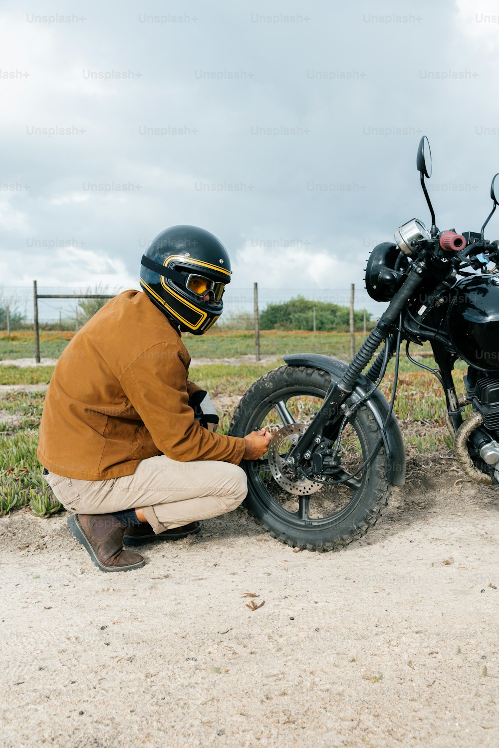 um homem ajoelhado ao lado de uma motocicleta
