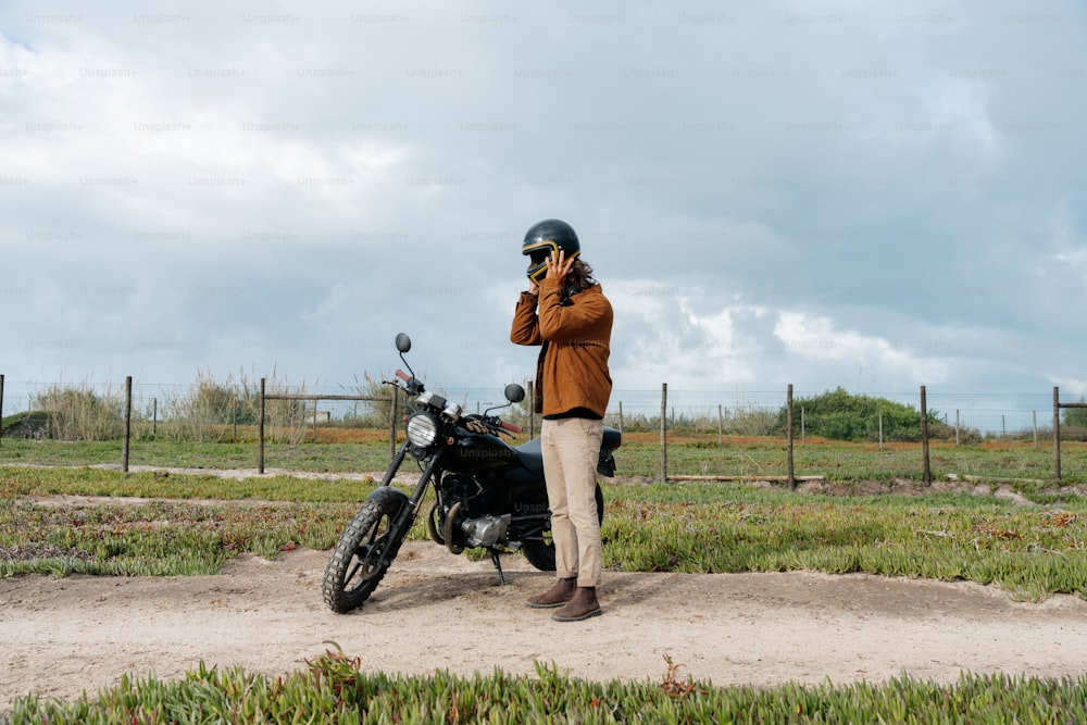 Un hombre parado al lado de una motocicleta hablando por teléfono celular