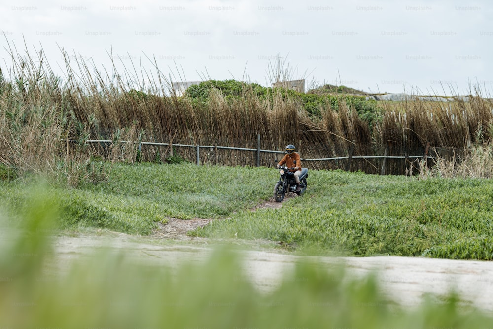 a man riding a motorcycle through a lush green field