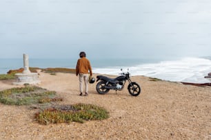 a man standing next to a motorcycle on a beach