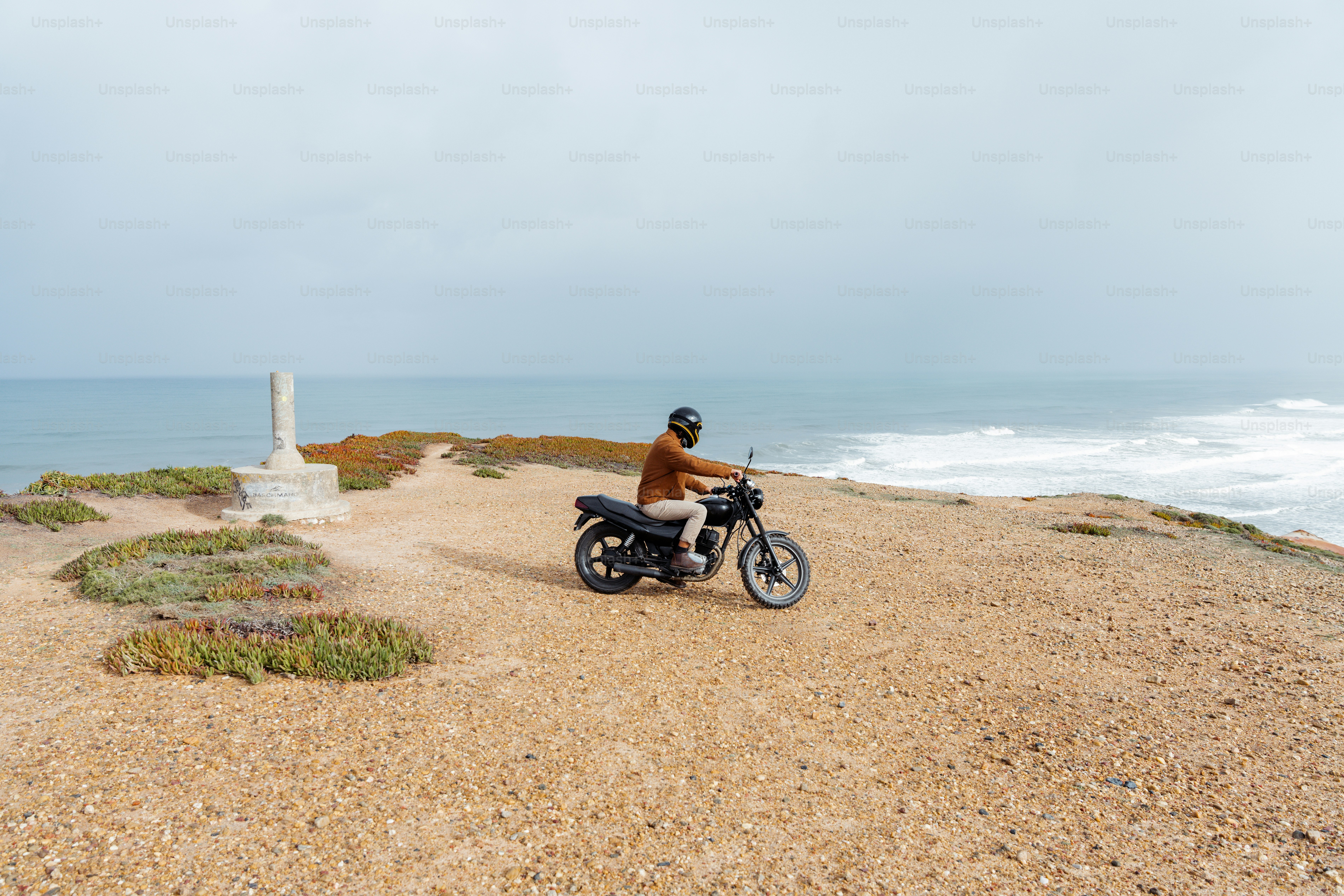 a man riding a motorcycle on top of a sandy beach