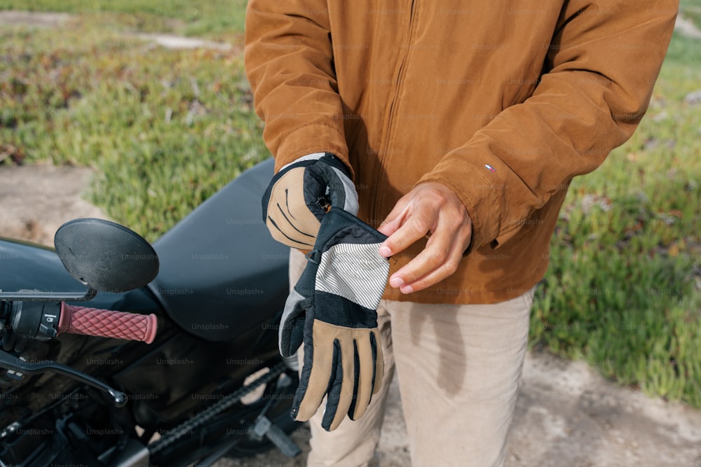 a man standing next to a motorcycle holding a glove