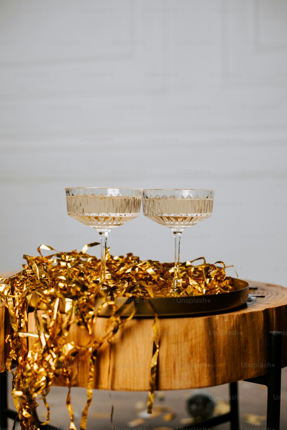 two champagne glasses on a table with gold streamers
