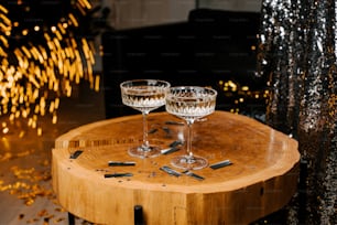 duas taças de vinho sentadas em uma mesa de madeira