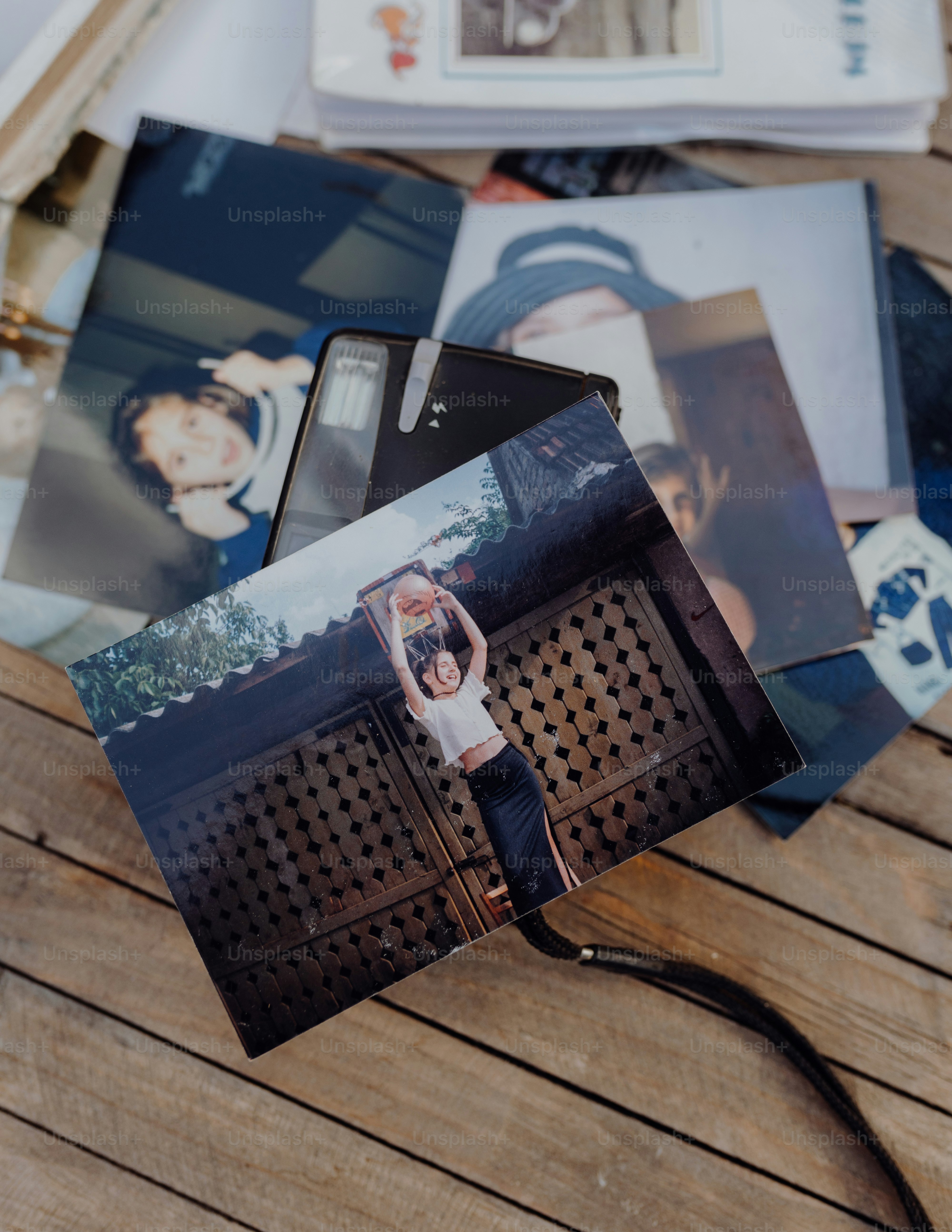 a wooden table topped with photos and a cell phone