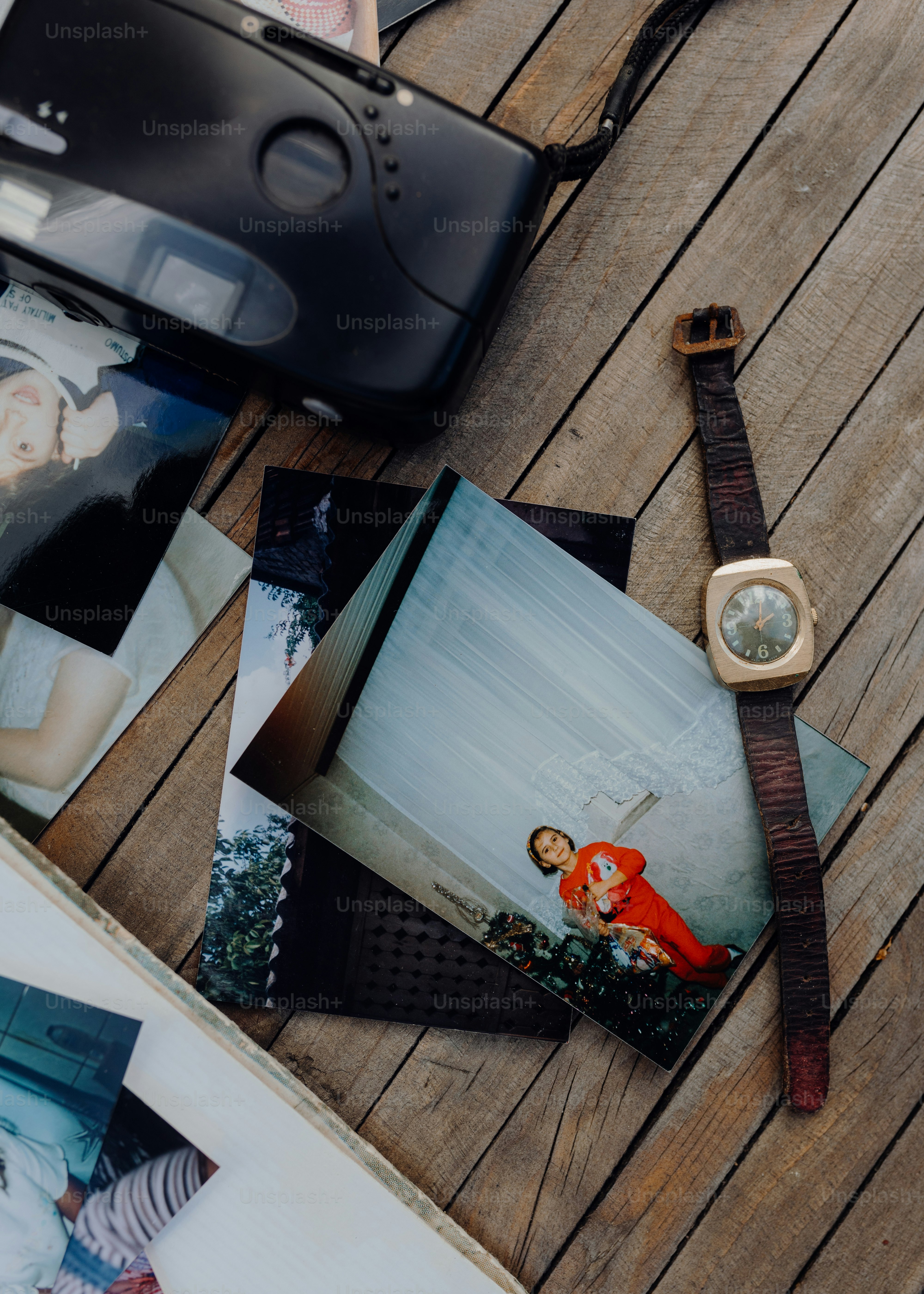 a wooden table topped with photos and a watch