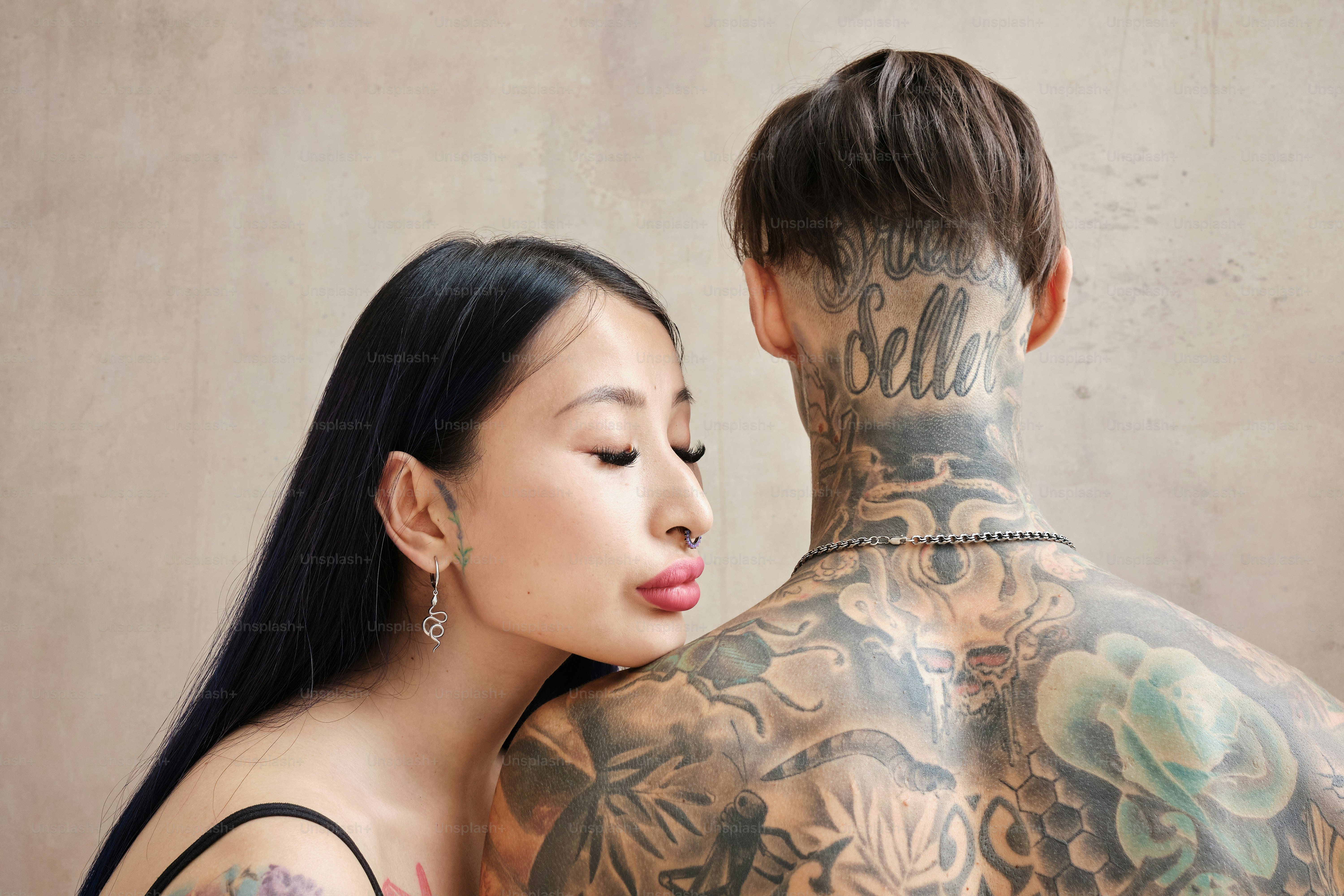 A couple of tattooed people standing together in a gentle embrace.