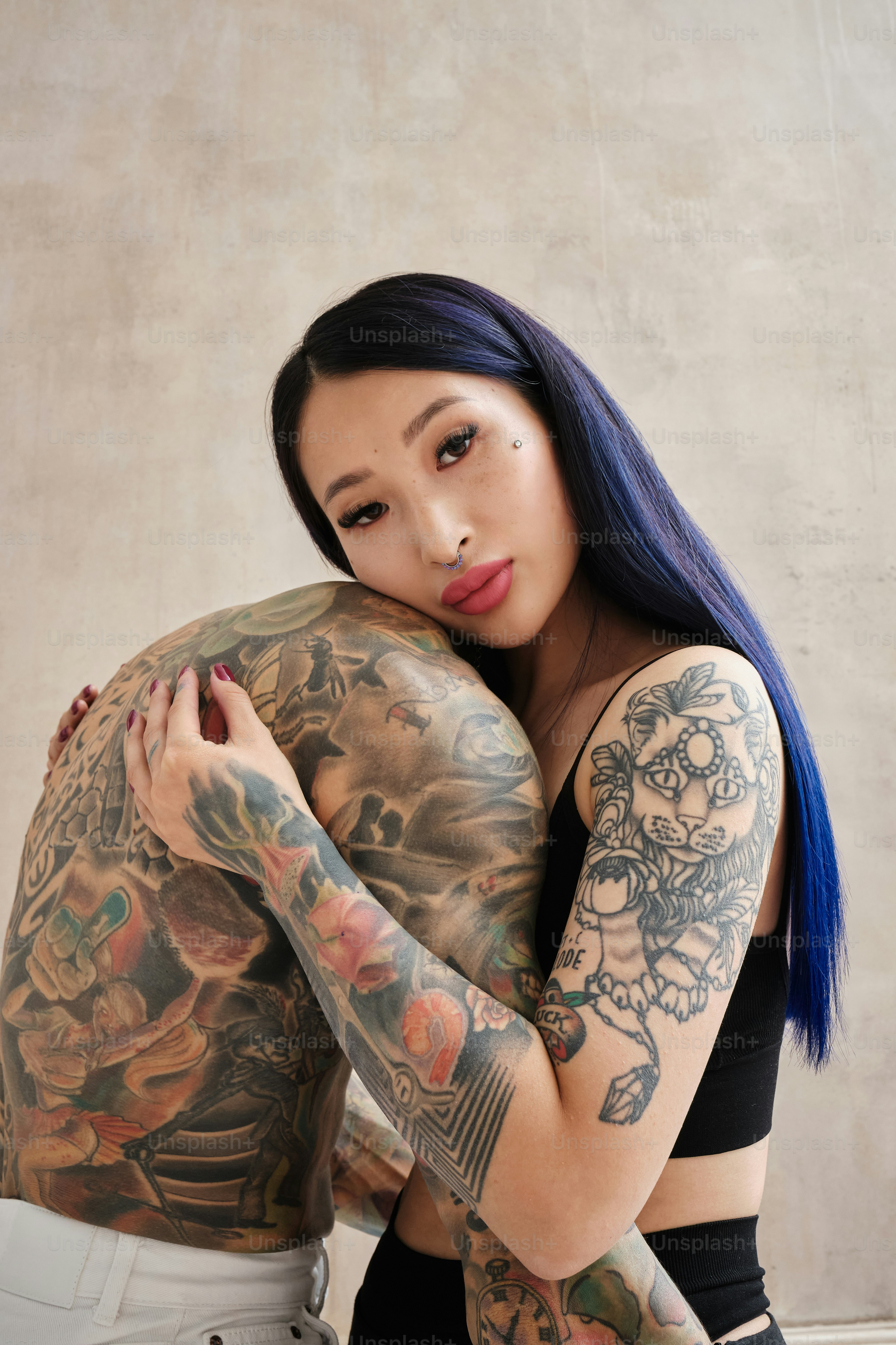 A couple of tattooed people standing together in a gentle embrace.