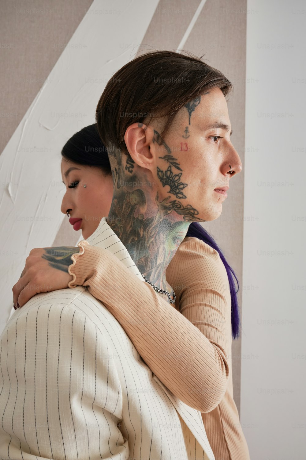 a woman with a tattoo on her neck hugging a man